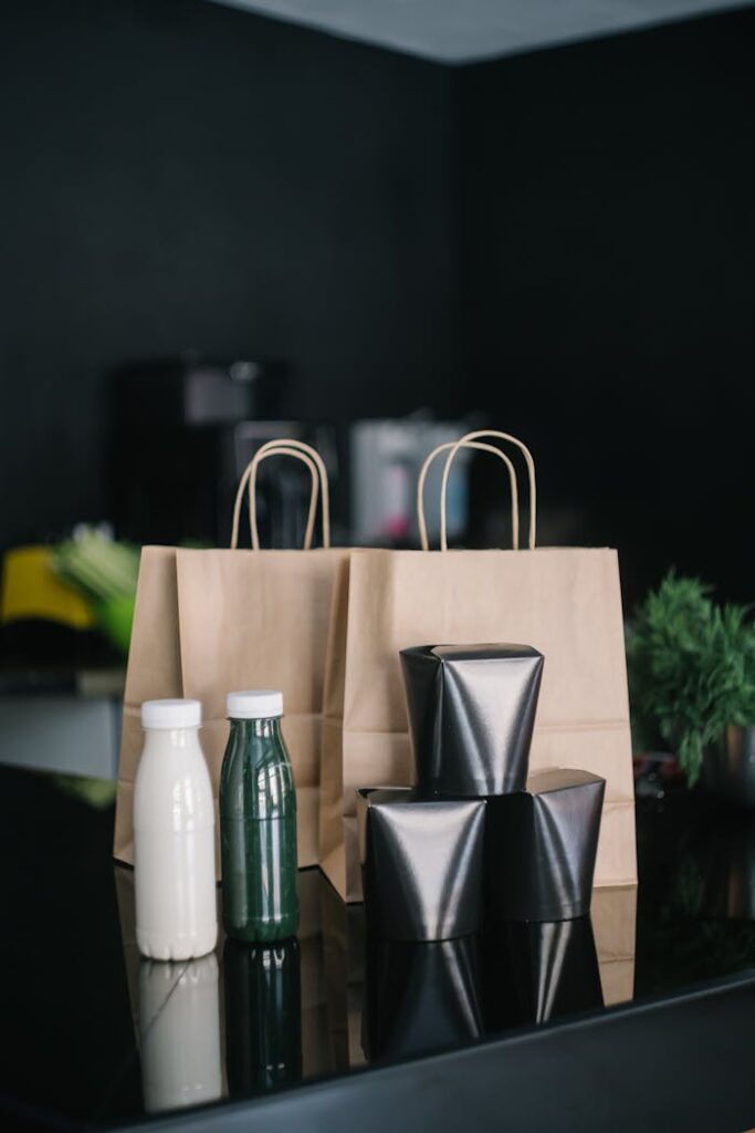 Stylish delivery setup with paper bags and bottles on a black table.
