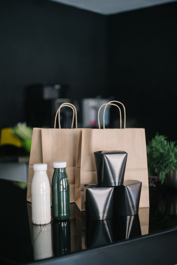 Stylish delivery setup with paper bags and bottles on a black table.